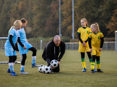 Jenter spiller fotball med en pappa som trenger. Foto